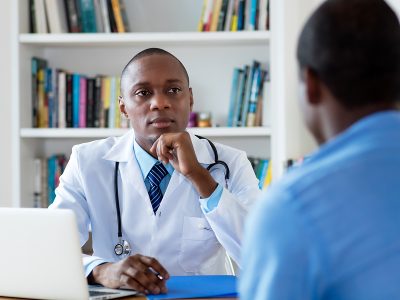 African American Doctor Listening To Problems Of Male Patient At African american doctor listening to problems of male patient at hospital